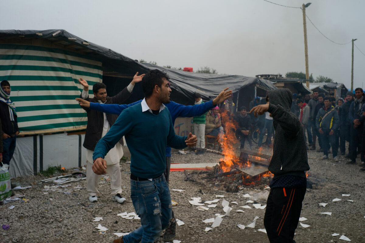 De jeunes afghans dansent autour d'un feu, la veille de l'opération d'évacuation du camp de réfugiés de Lande à Calais, le 23 octobre 2016 / © Rafael Yaghobzadeh