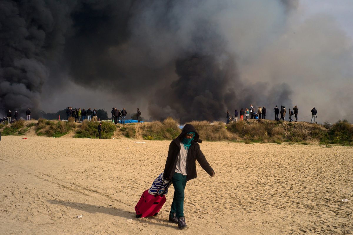 Un Soudanais munis de ses affaires personnelles s'échappe suite aux multiples incendies qui se sont déclarés dans le camps de réfugiés, lors du troisième jour de l'opération de démantèlement à Calais, le 26 octobre 2016 