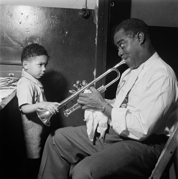 1G08V4_SCHWAB ÉRIC SCHWAB Le jazzman américain Louis Armstrong joue pour un petit garçon dans sa loge, avant un spectacle en 1947 dans un cabaret de jazz de New York