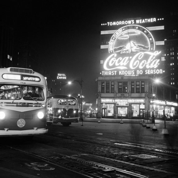 1PN8QF ÉRIC SCHWAB Des bus circulent la nuit en mars 1947 sur Columbus Circle où une publicité pour Coca-Cola annonce la météo du lendemain, à Manhattan, New York.