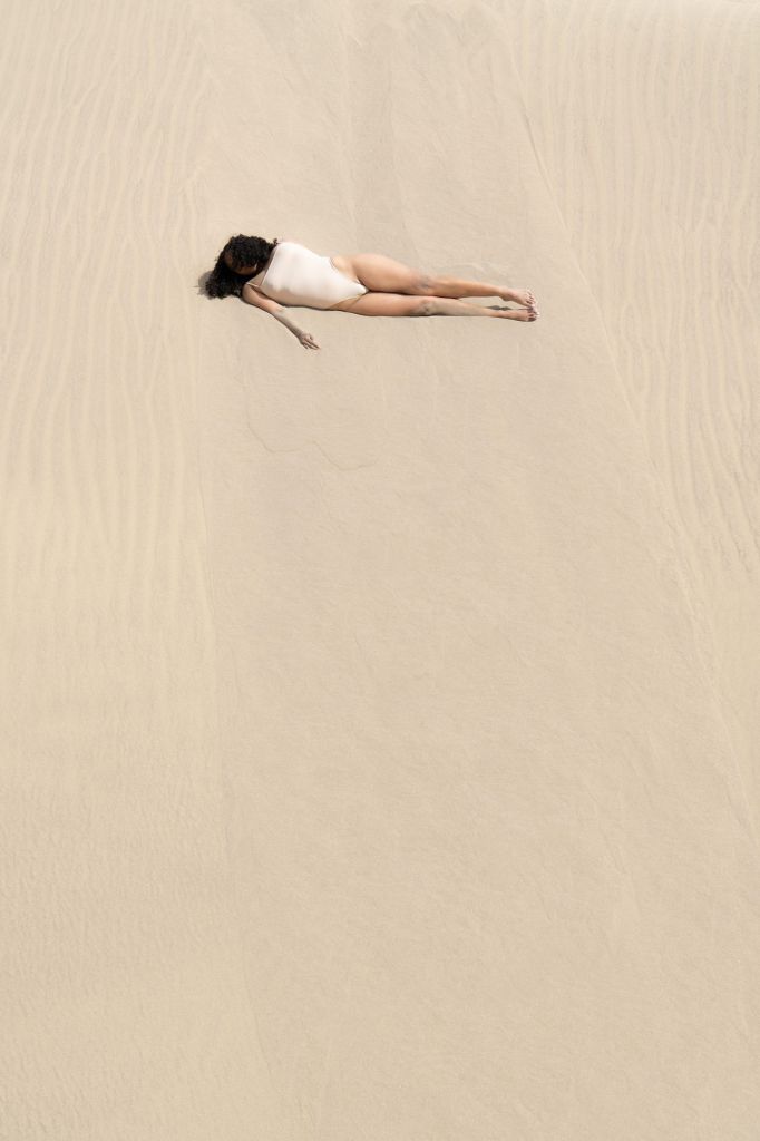 Une femme allongée dans le sable. De la série Nothing half, nothing whole de Verdiana Albano.