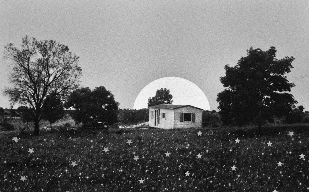 Une photo en noir et blanc d'une maison de campagne la nuit