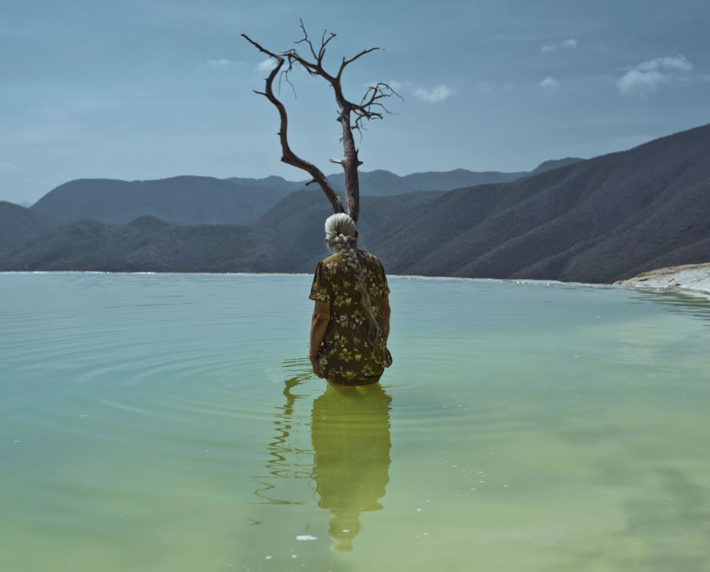 Une femme se baigne à moitié à côté d'un arbre immergé dans l'eau par Cristina de Middel