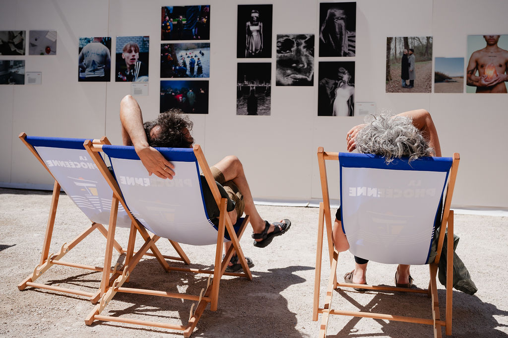 Deux personnes assises devant l'exposition 10/10, cour de l'Archevêché, durant les Rencontres d'Arles