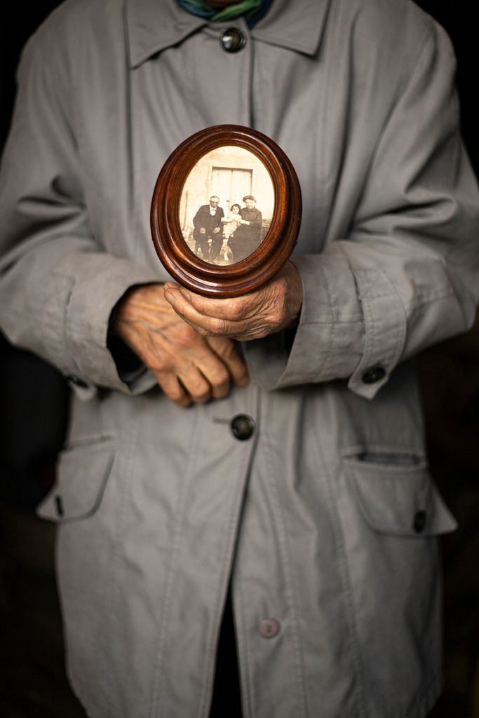 Photographie réalisée par Marjorie Gosset montrant un femme tenant une vieille photo de famille entre ses mains.