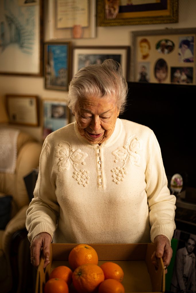 Photographie réalisée par Marjorie Gosset montrant une femme âgée portant une caisse d'oranges.