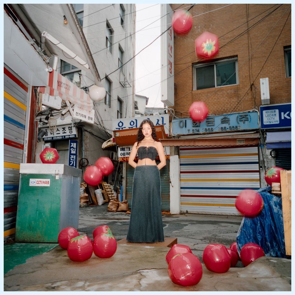 Une femme pose dans une rue de Séoul, en Corée du Sud. Des tomates géantes l'entourent.