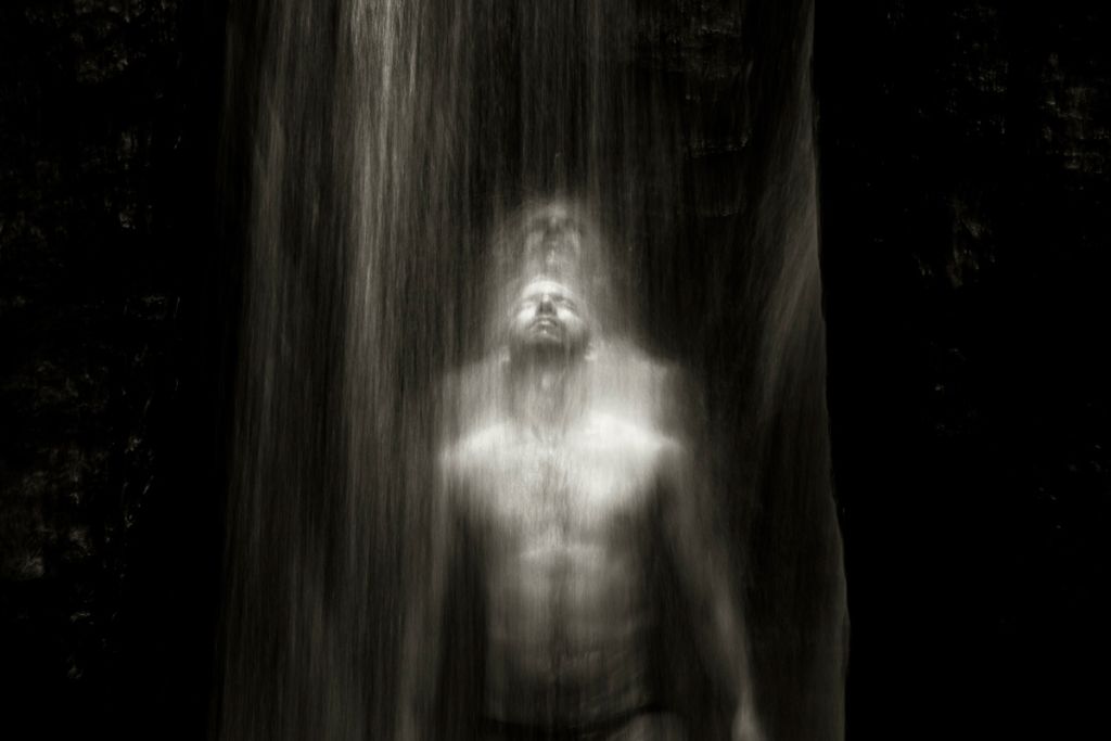 Homme sous une cascade semblant se dédoubler dans le mouvement photographié par Rafael Fabrés.