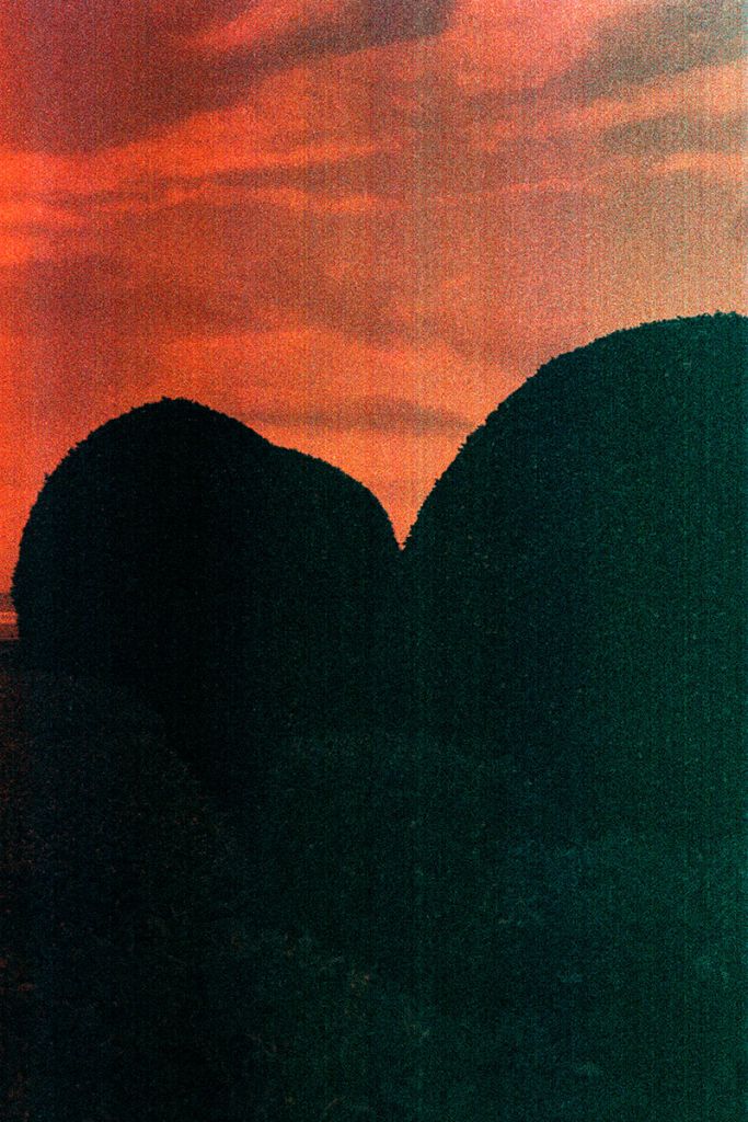 Des formes rocheuses prises à contre-jour, qui dessinent le début d'un cœur. Photo capturée avec un filtre rouge-orangé