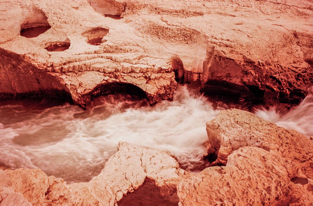 Un ruisseau coule entre des rochers, photo capturée avec un filtre orangé