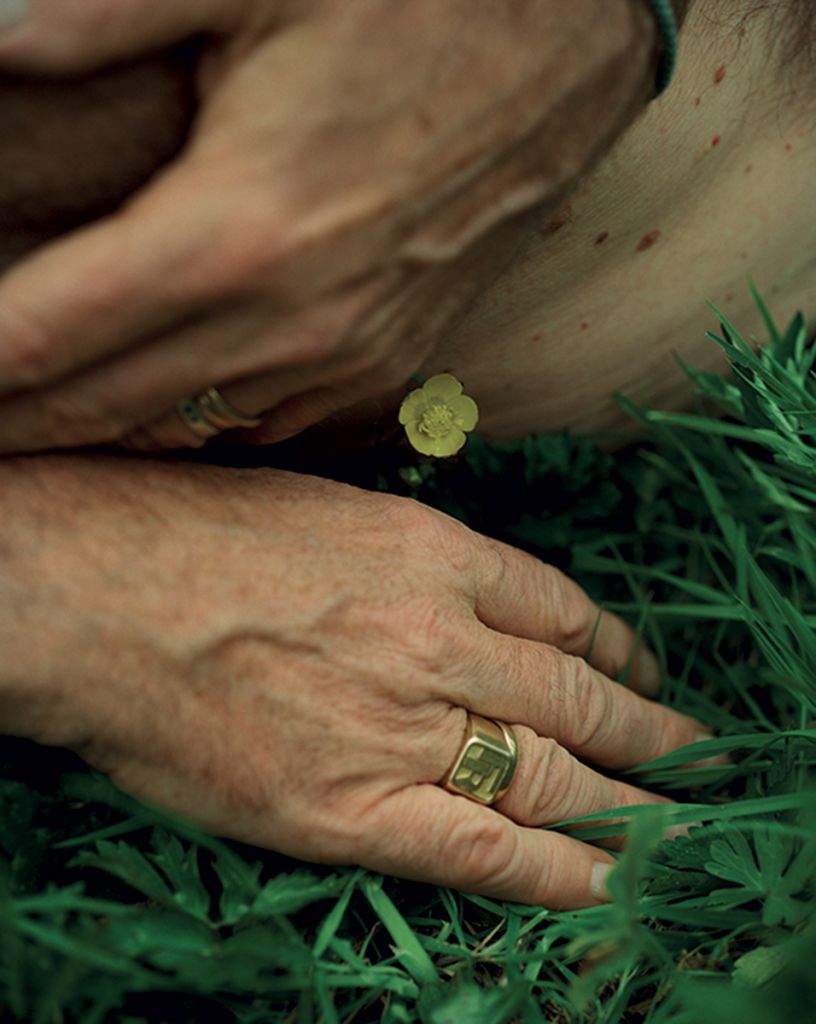 Photographie de Daniel Jack Lyons montrant des mains dans l'herbe, avec un bouton d'or