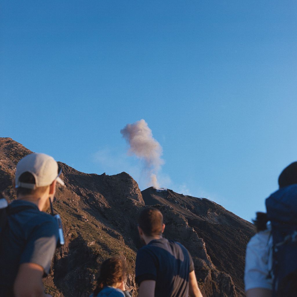 Personnes observant un volcan dégageant de la fumée