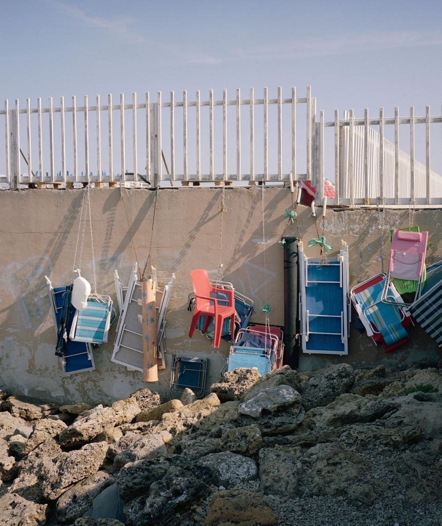 Des chaises sont suspendues à un grillage.