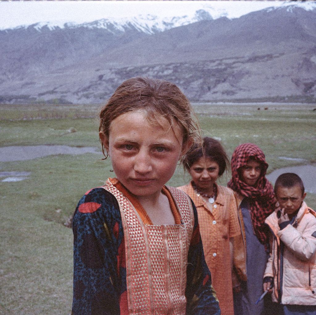 Des jeunes filles afghanes, debout au milieu d'une plaine en montagne, regardent l'objectif