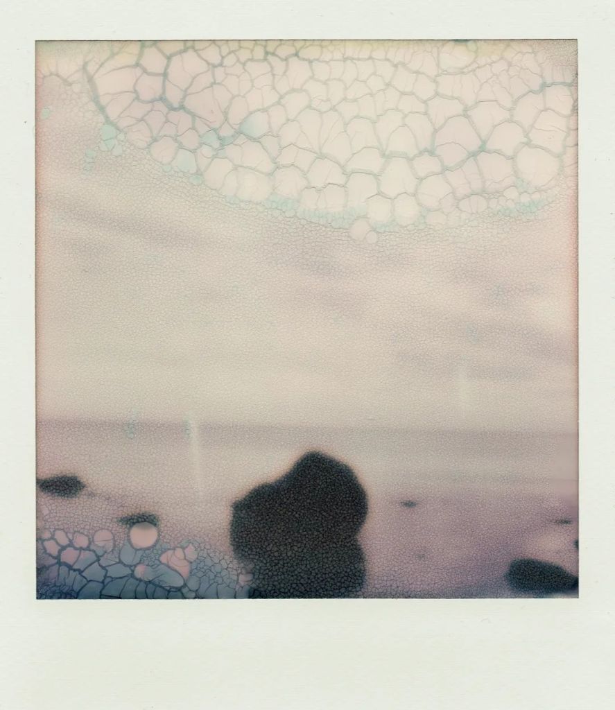 Polaroid d'une roche en face de la mer. Film soup.