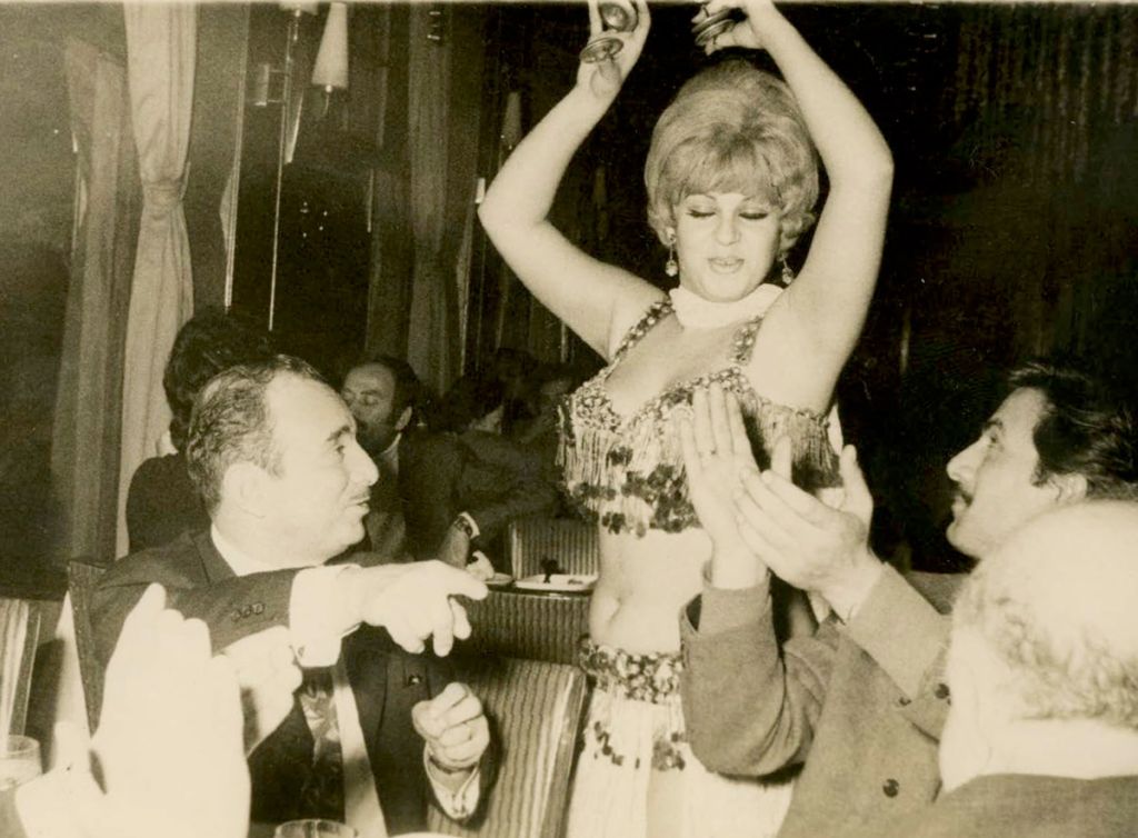 Photographie montrant un couple au restaurant dans les années 1960-1970 avec une danseuse.