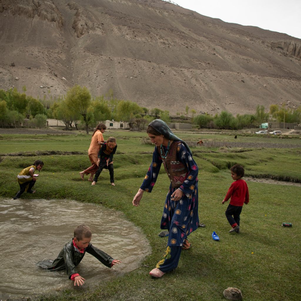 Photographie de Kiana Hayeri montrant une femme et des enfants jouant dans des flaques d'eau en Afghanistan.