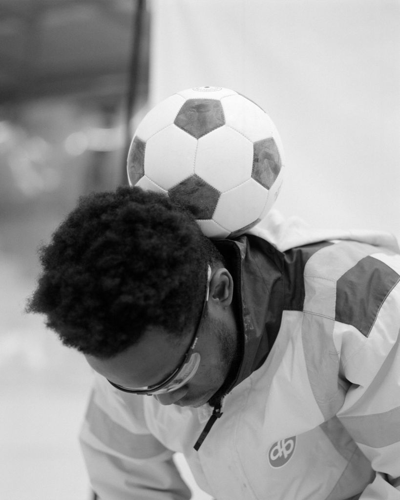 Un ouvrier de chantier avec un ballon de football derrière la tête.