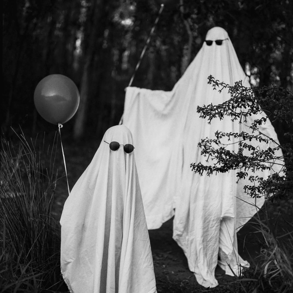 Photo en noir et blanc d'une famille déguisée en fantômes à lunettes de soleil.