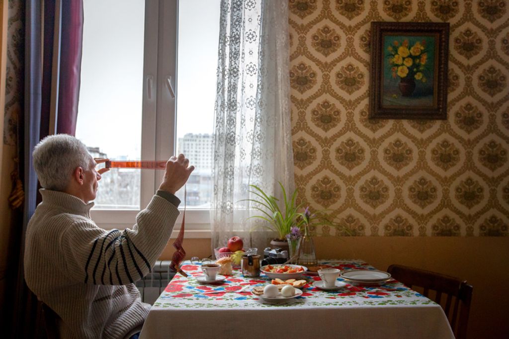 Photographie de Diana Markosian montrant son père regardant les négatifs d'une pellicule