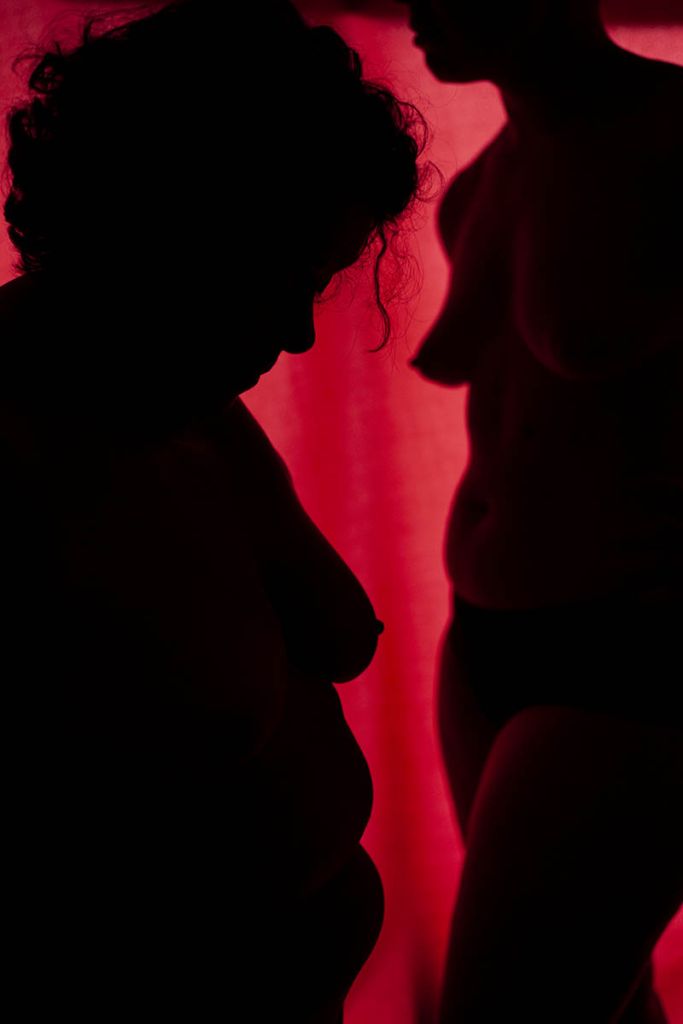 profil de deux corps de femmes nus dans une lumière rouge