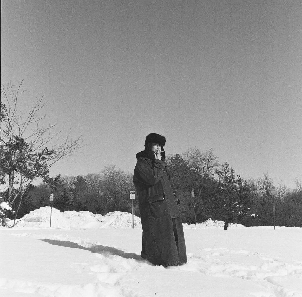 Personne allumant une cigarette dans la neige. En noir et blanc.