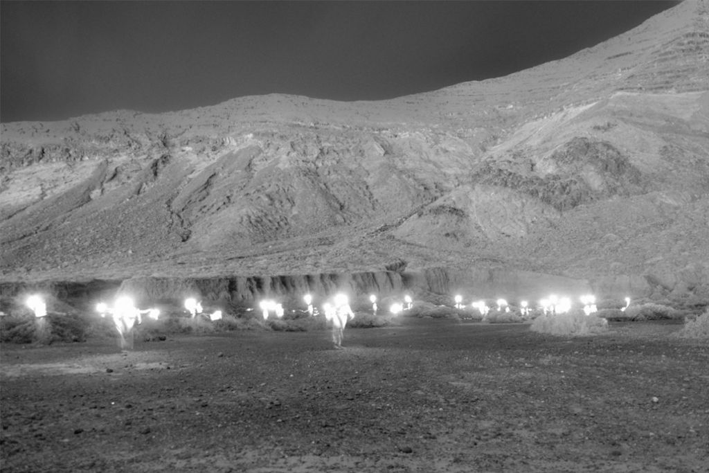 plusieurs silhouettes lumineuses au pied d'une montagne